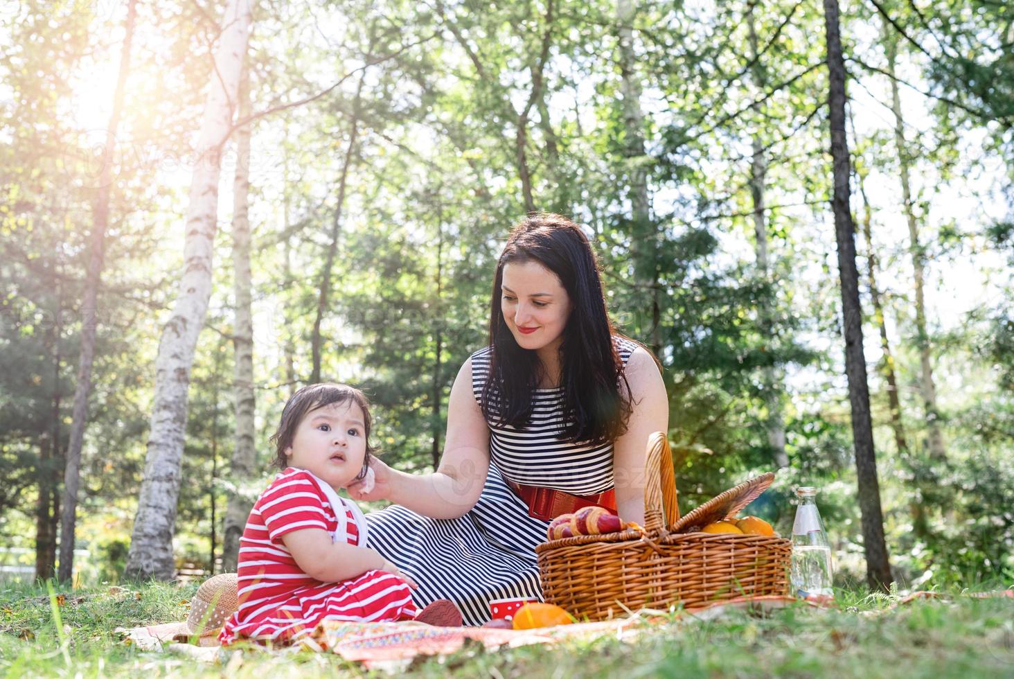 famiglia interrazziale di madre e figlia nel parco che fanno un picnic foto