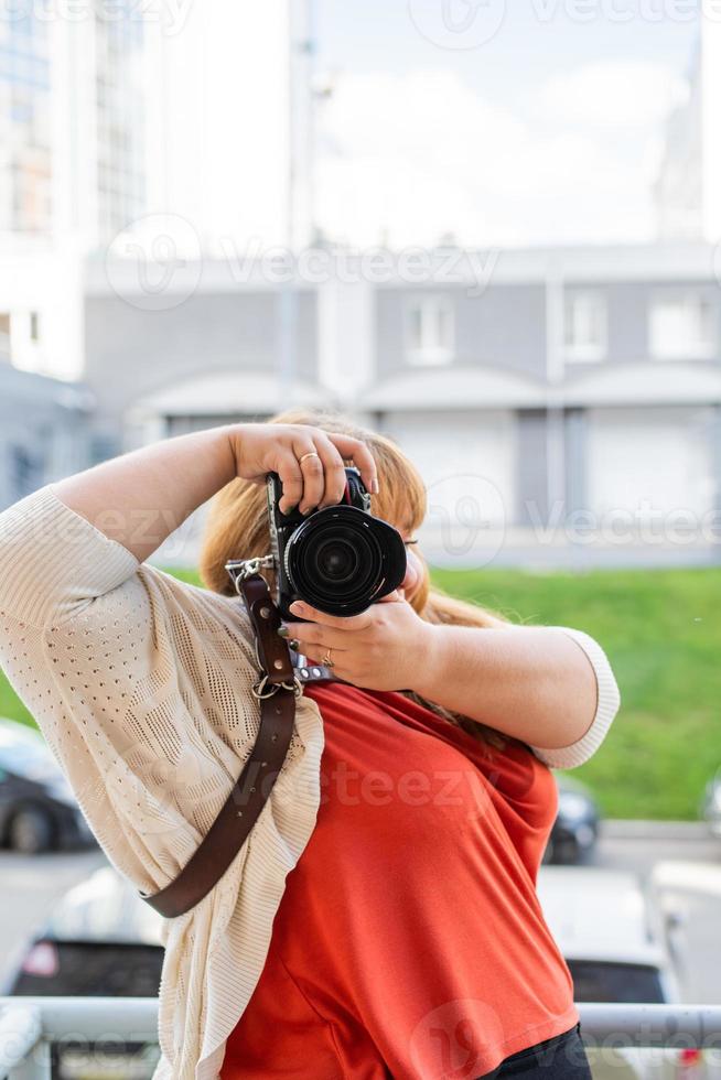 ritratto di donna sovrappeso che scatta foto con una macchina fotografica all'aperto