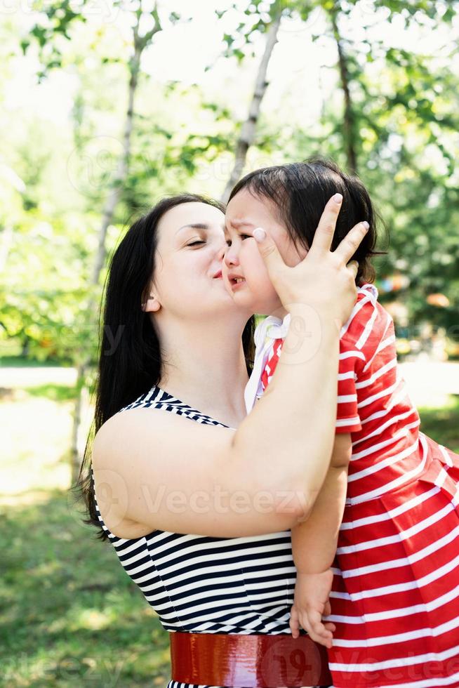 madre che bacia e calma la sua bambina foto