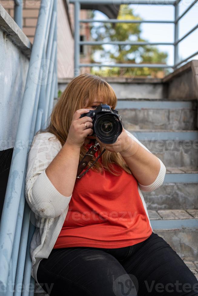 ritratto di donna sovrappeso che scatta foto con una macchina fotografica all'aperto
