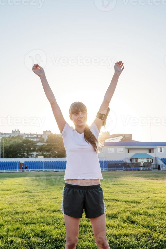 giovane ragazza sportiva in piedi sulla pista alzando le braccia foto