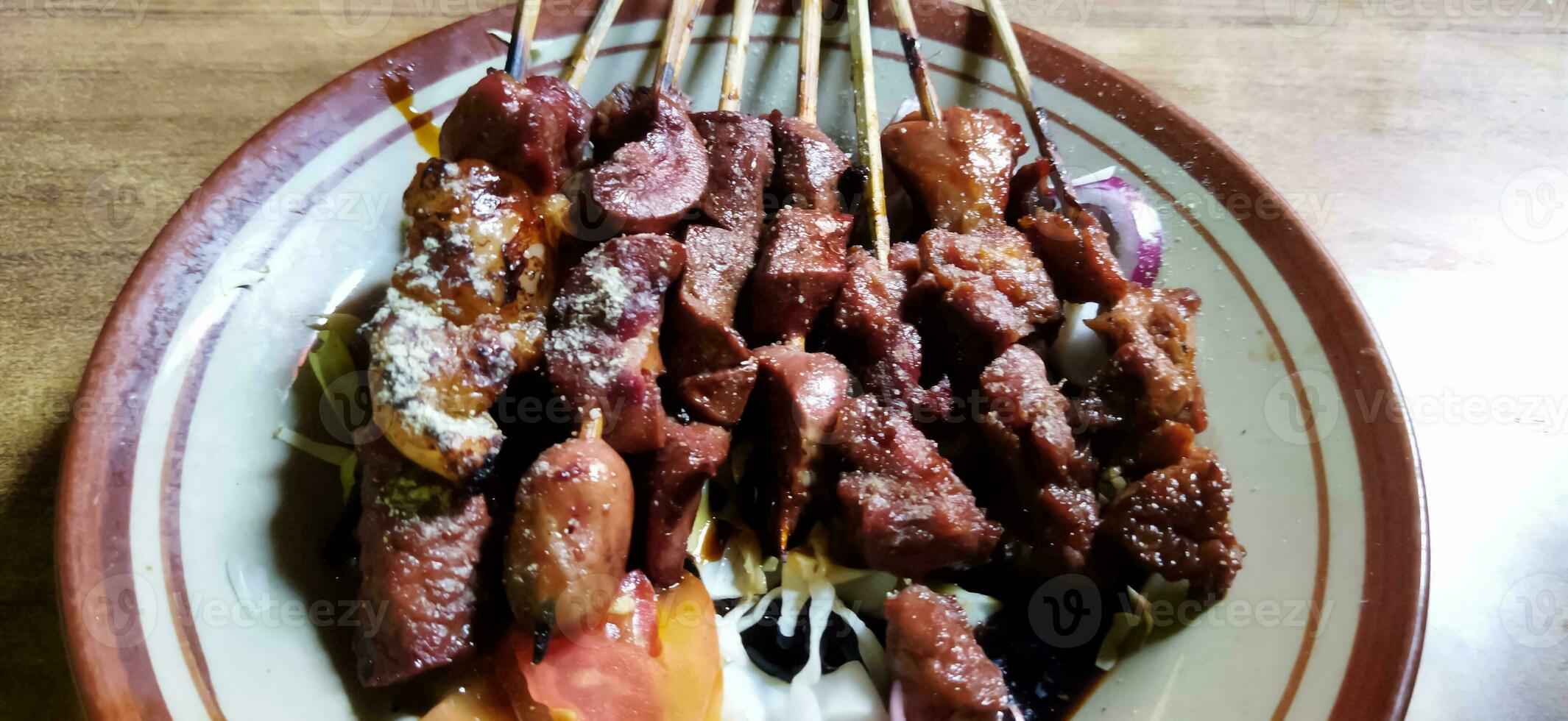 satay o saziare kambing, carne satay servito con fetta cavolo, rosso cipolla, peperoncino, pomodori, con soia salsa su piatto. selettivo messa a fuoco Immagine foto