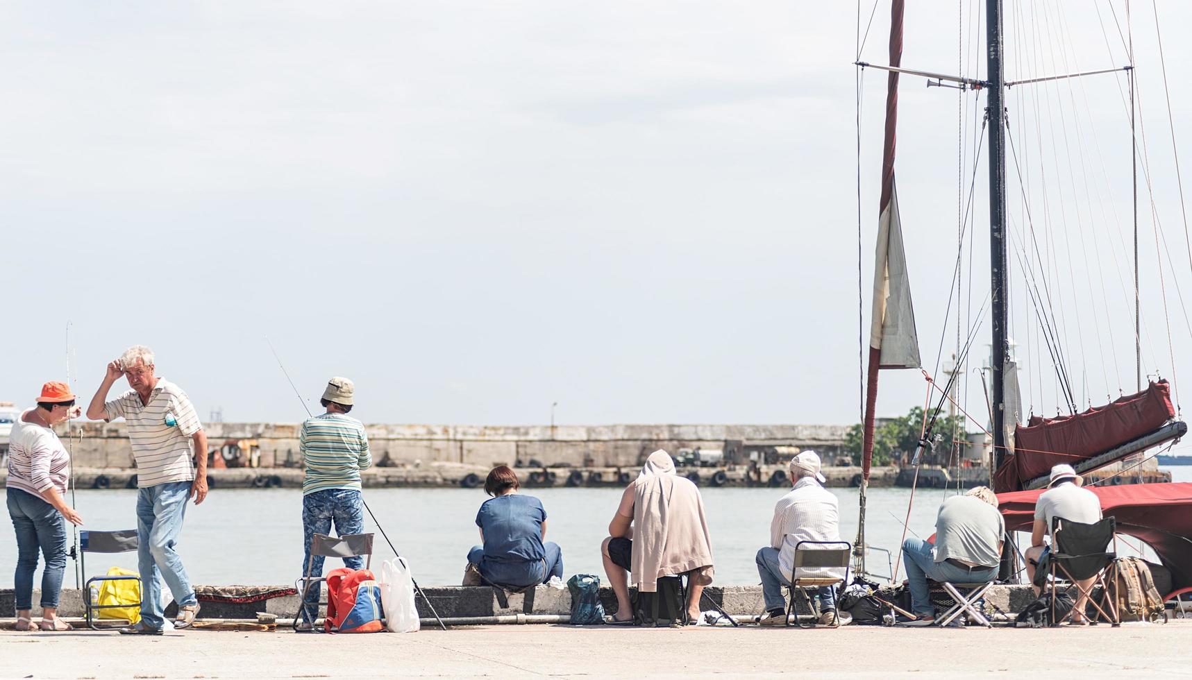 yalta 2021- persone che pescano sull'argine, barche e yacht sullo sfondo foto