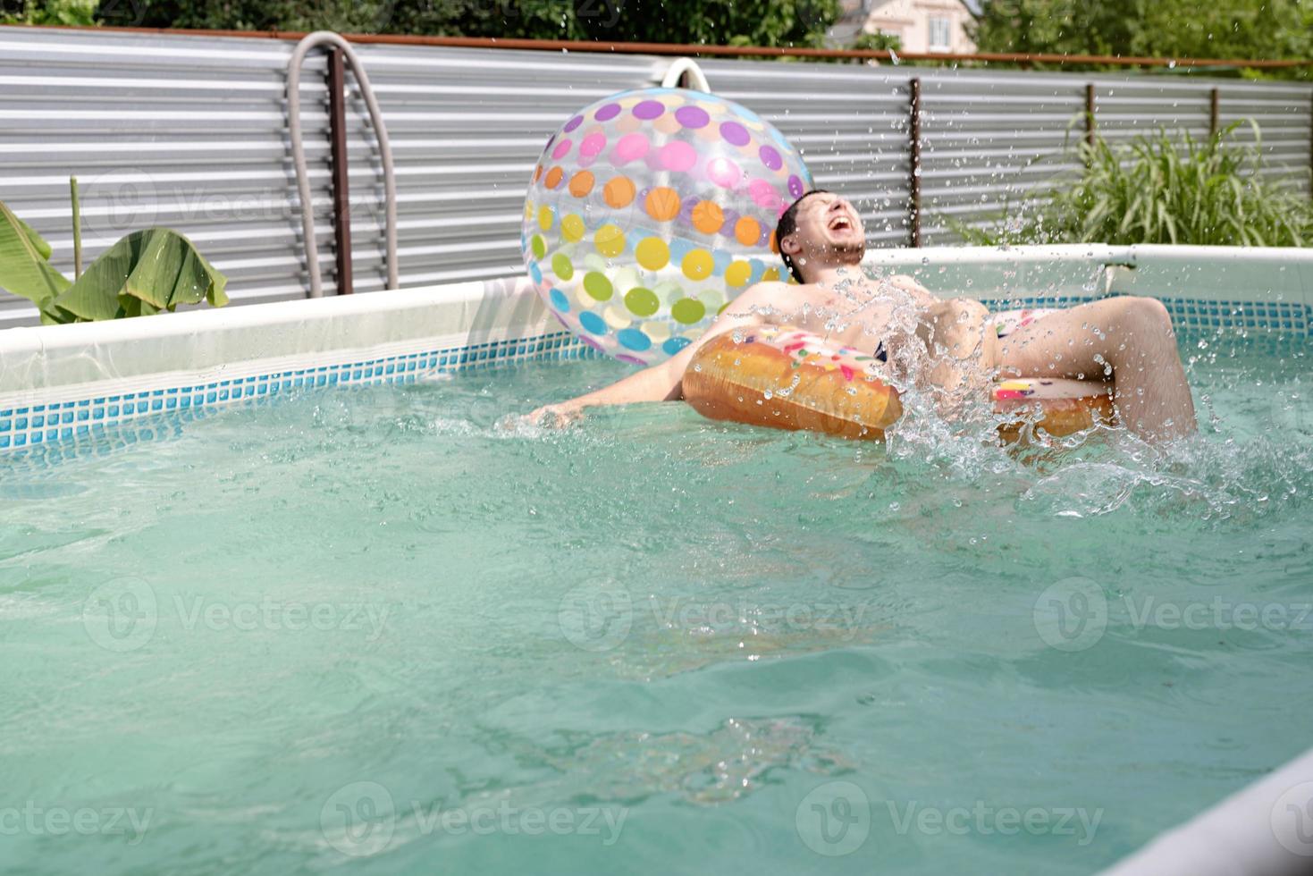 giovane che si diverte in piscina sul tubo gonfiabile da bagno foto