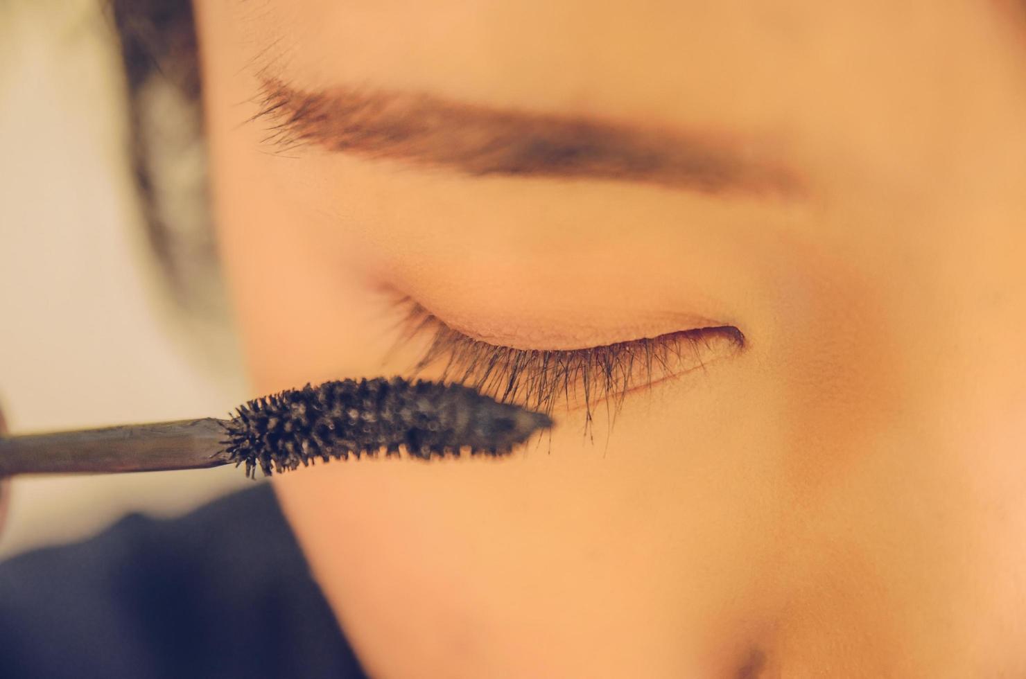 volto di bellezza della donna applicando il mascara sugli occhi dai cosmetici. foto