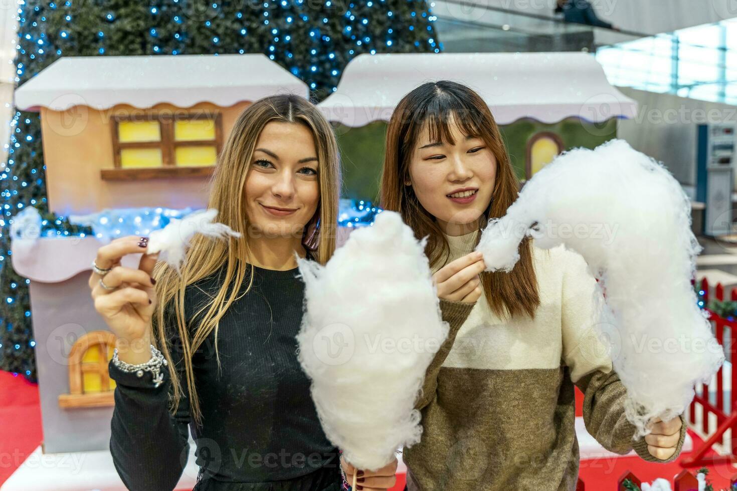 coppia di giovane multietnico donne mangiare allegro cotone caramella a un' festa. foto