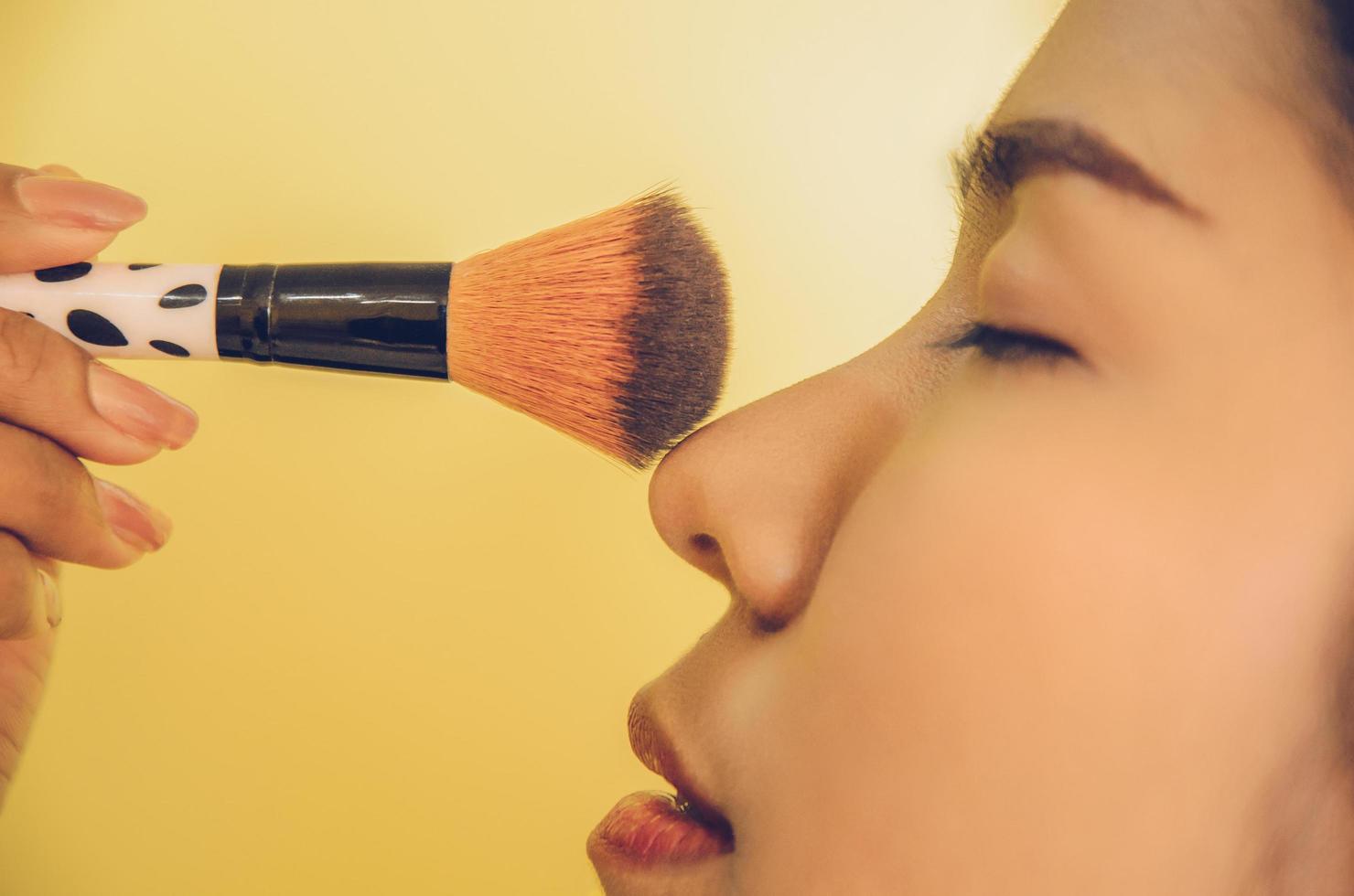 volto di bellezza della donna asiatica applicando i pennelli sulla pelle dai cosmetici. foto