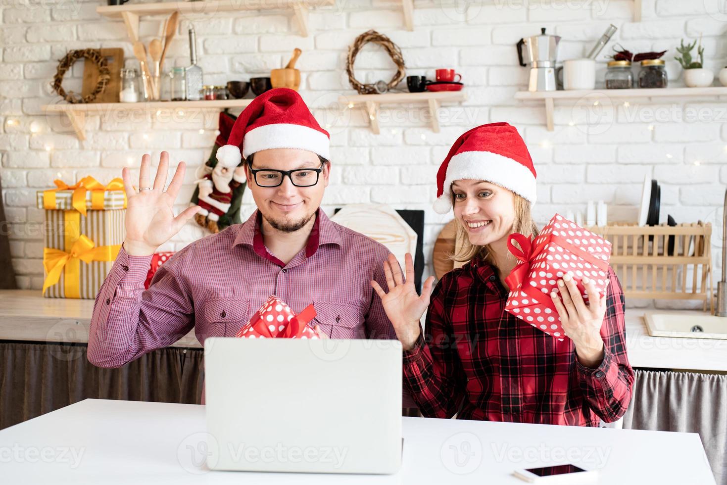 coppia in cappelli di Babbo Natale che saluta i loro amici in una videochiamata foto