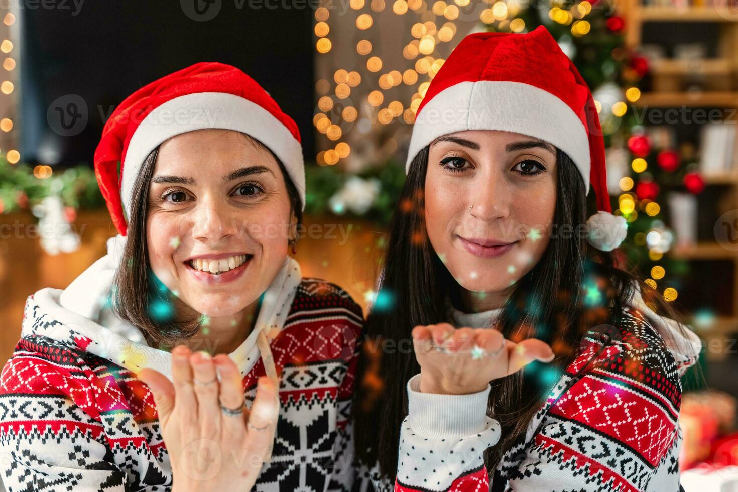 carino giovane donne vestito nel rosso cappello e Natale felpa soffiaggio coriandoli foto