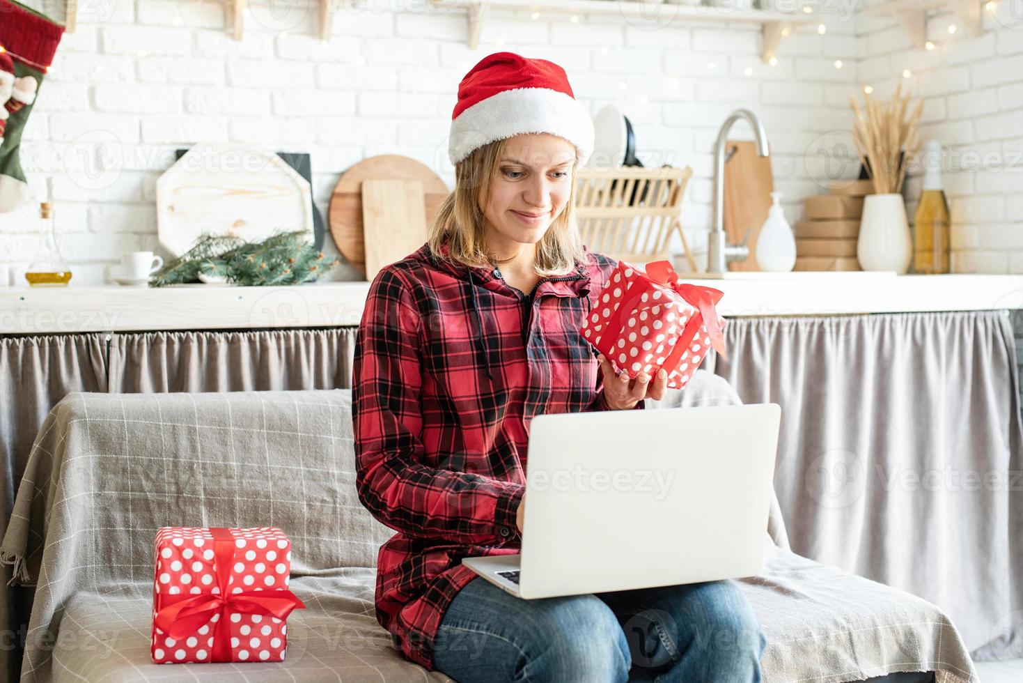 donna con cappello da Babbo Natale che saluta i suoi amici in video chat sul laptop foto