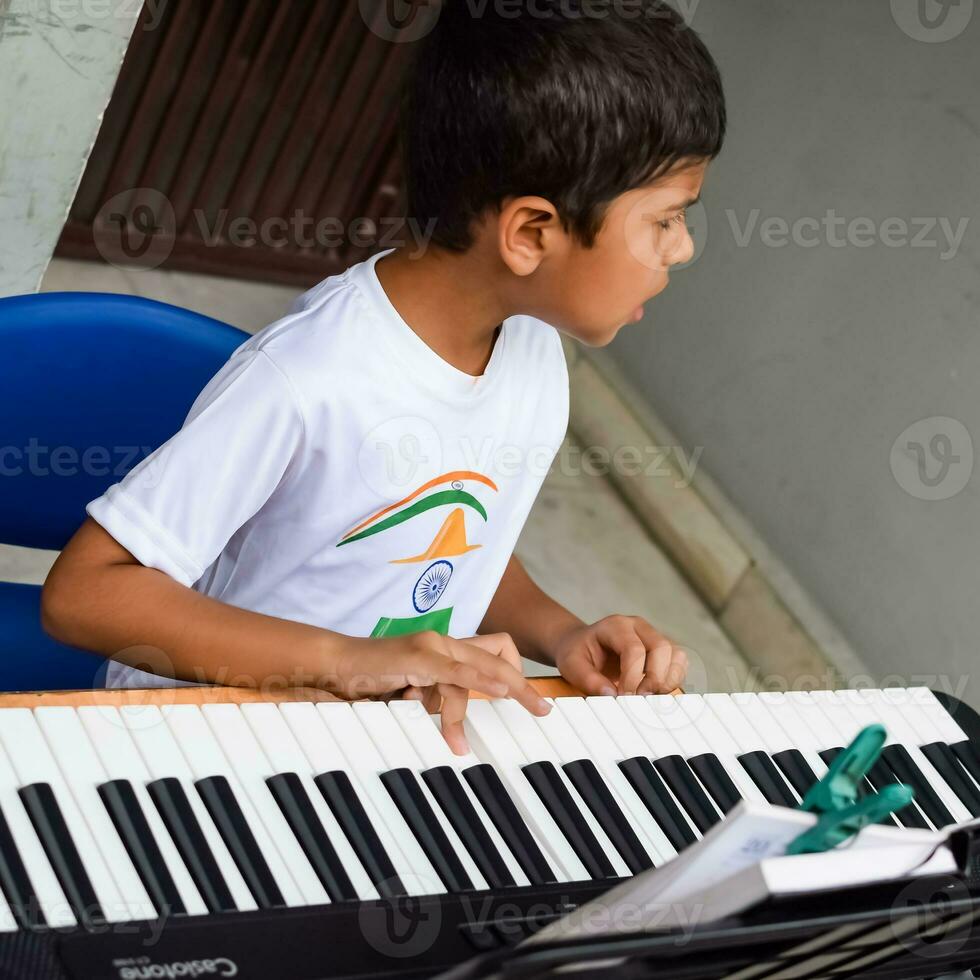 asiatico ragazzo giocando il sintetizzatore o pianoforte. carino poco ragazzo apprendimento Come per giocare pianoforte. del bambino mani su il tastiera interno. foto