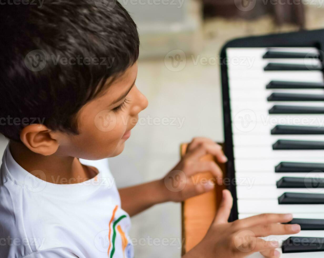 asiatico ragazzo giocando il sintetizzatore o pianoforte. carino poco ragazzo apprendimento Come per giocare pianoforte. del bambino mani su il tastiera interno. foto