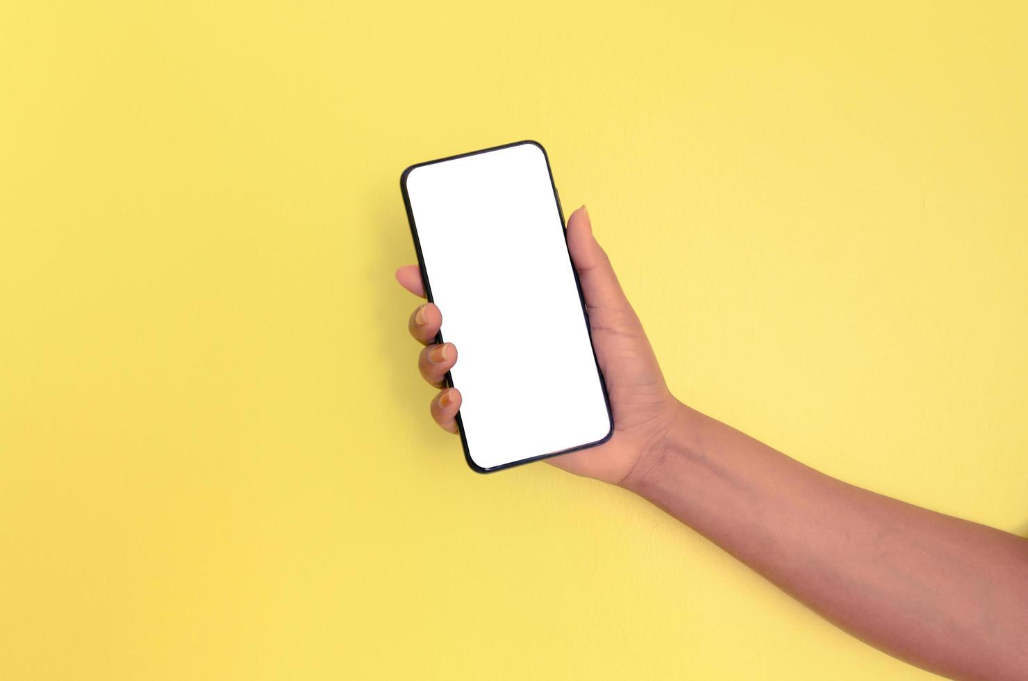 una mano che tiene uno smartphone con sfondo bianco. foto