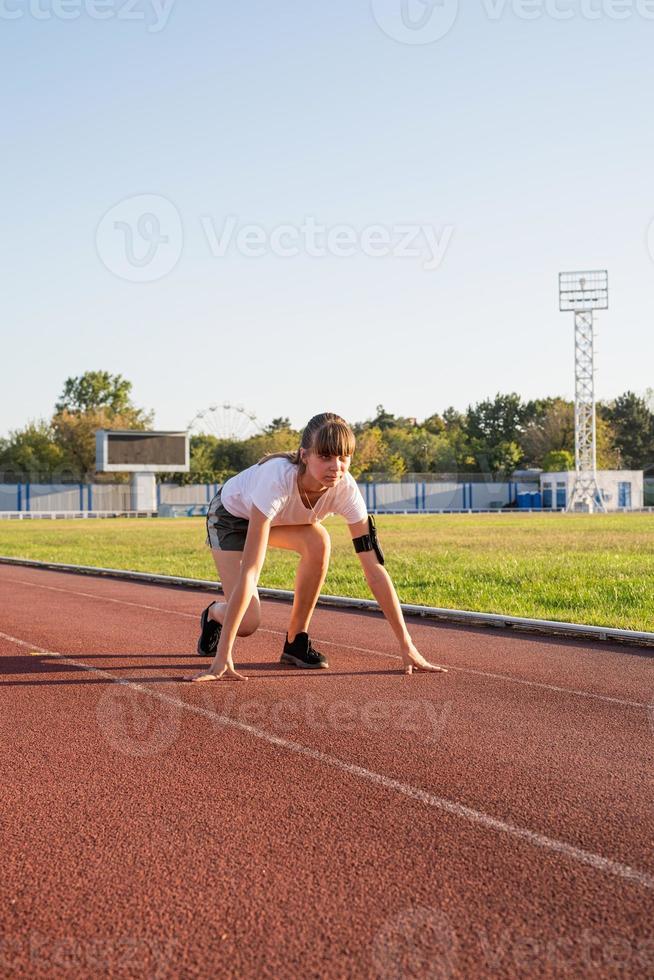 donna in posizione di partenza, pronta a correre sulla pista dello stadio foto