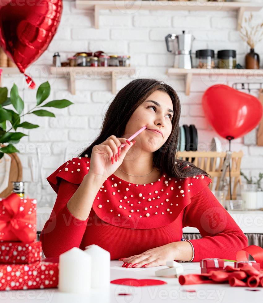 donna che scrive una lettera d'amore seduta nella cucina decorata foto