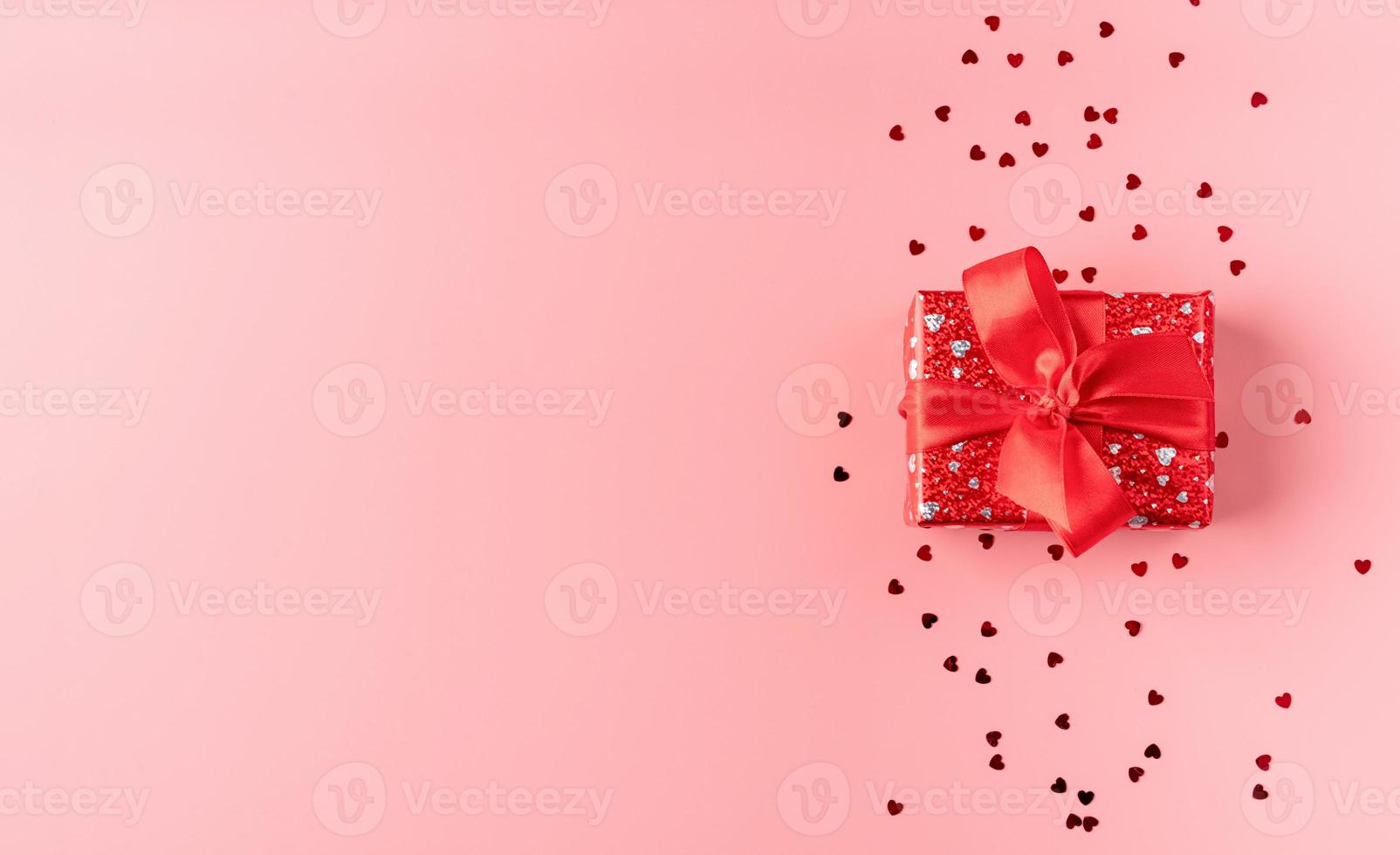 confezione regalo rossa con fiocco in corda su sfondo rosa foto