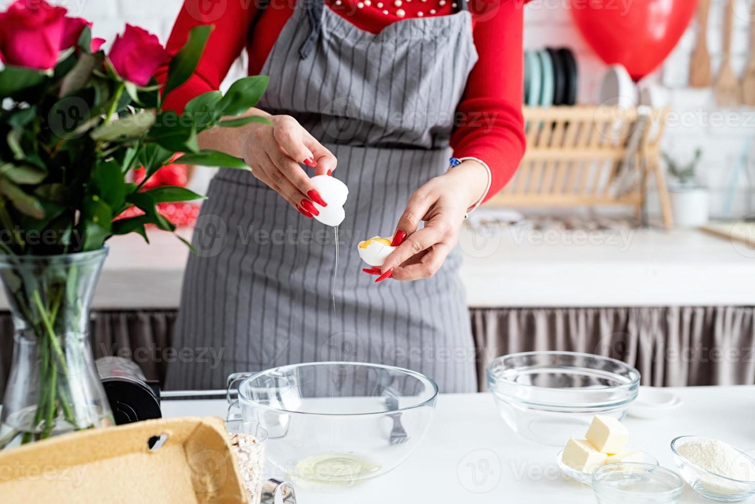 donna in abito rosso e grembiule grigio che prepara la cucina di san valentino foto