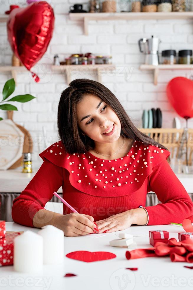 donna che scrive una lettera d'amore seduta nella cucina decorata foto