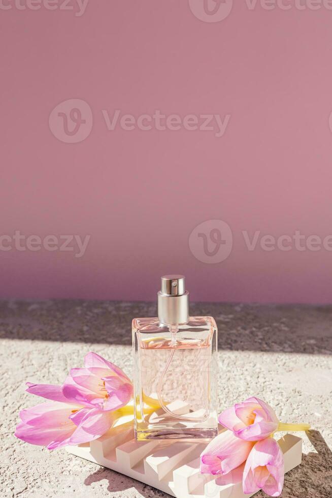 un' trasparente bottiglia di cosmetico spray o profumo sta su un' bianca sbalzato podio con primavera fiori. Prodotto presentazione. davanti Visualizza. foto