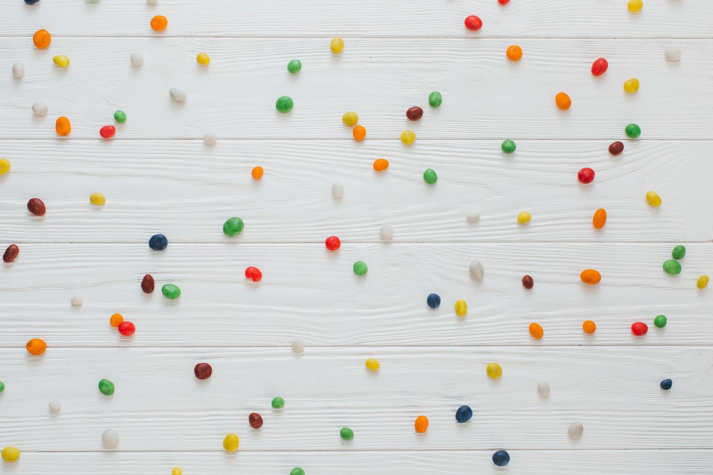 molte caramelle dolci multicolori su fondo di legno bianco. foto