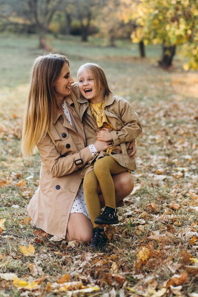 madre e figlia che si siedono e si divertono nel parco autunnale. foto