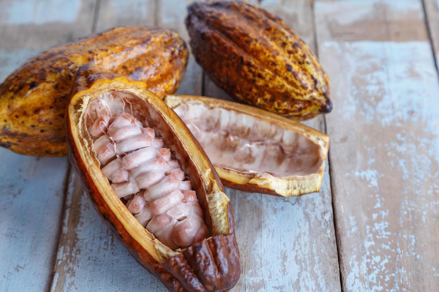 baccelli di cacao freschi e foglie di cacao su fondo in legno foto