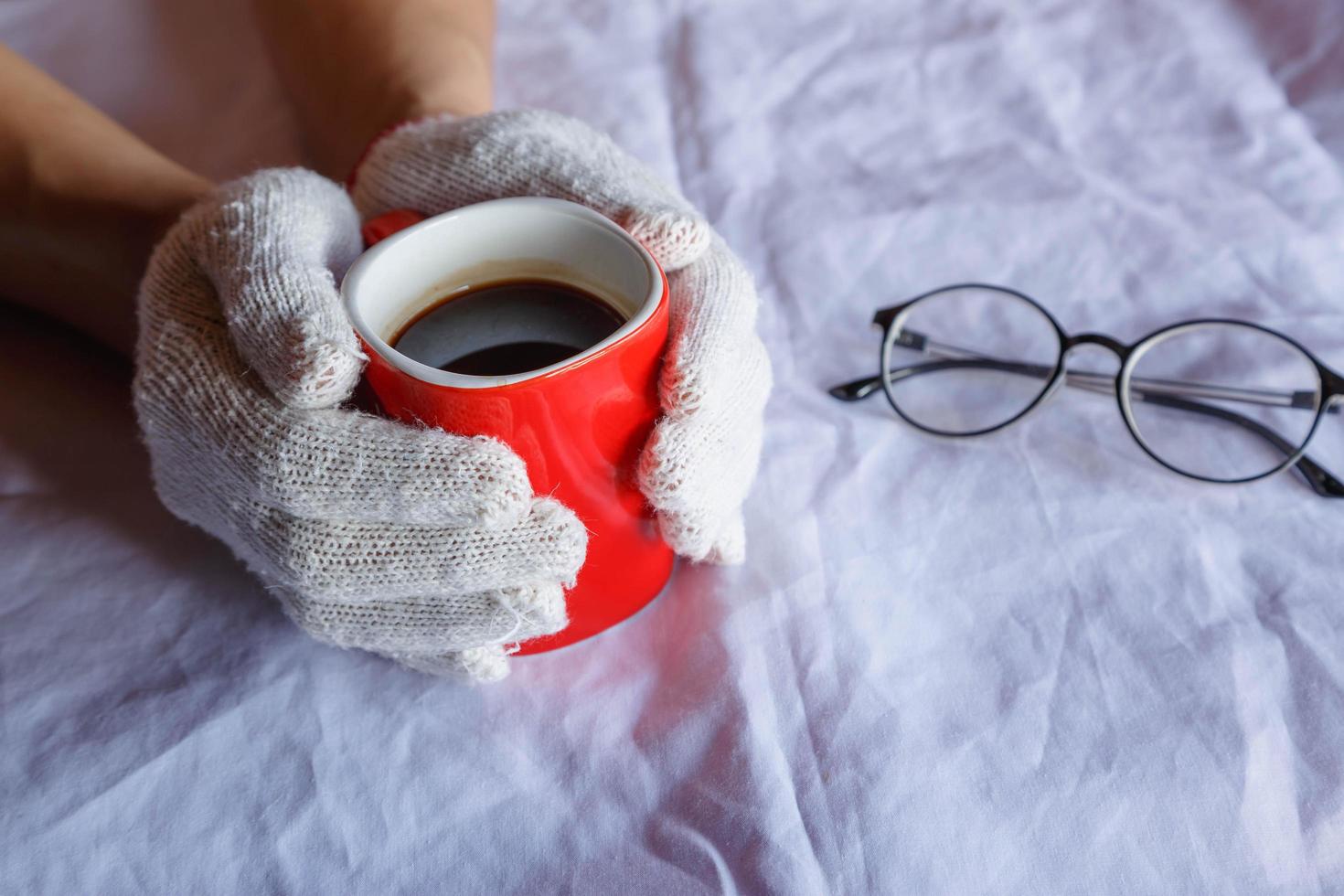 tazza di caffè rossa in mano indossando guanti in inverno foto
