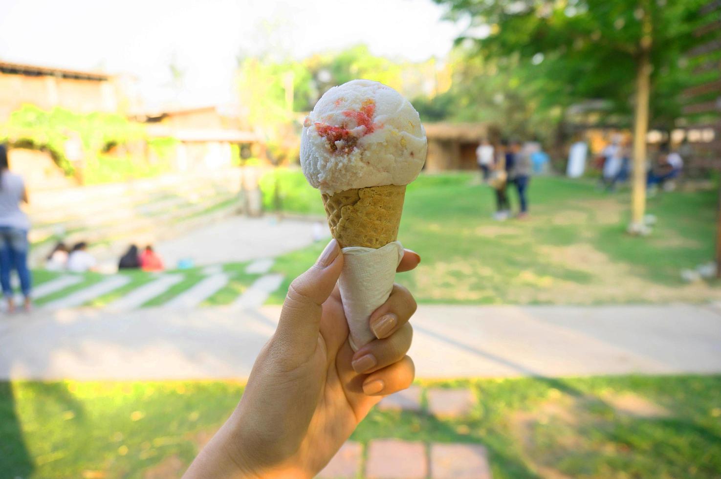 mano di donna che tiene cono di wafer con gelato ai frutti di bosco foto