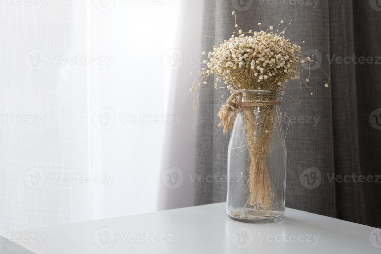 fiore secco in una bottiglia di vaso di vetro trasparente in soggiorno foto