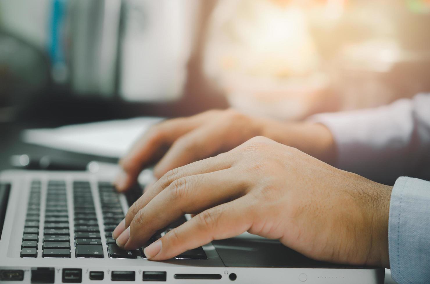 mano dell'uomo utilizzando il computer portatile sul tavolo a casa foto