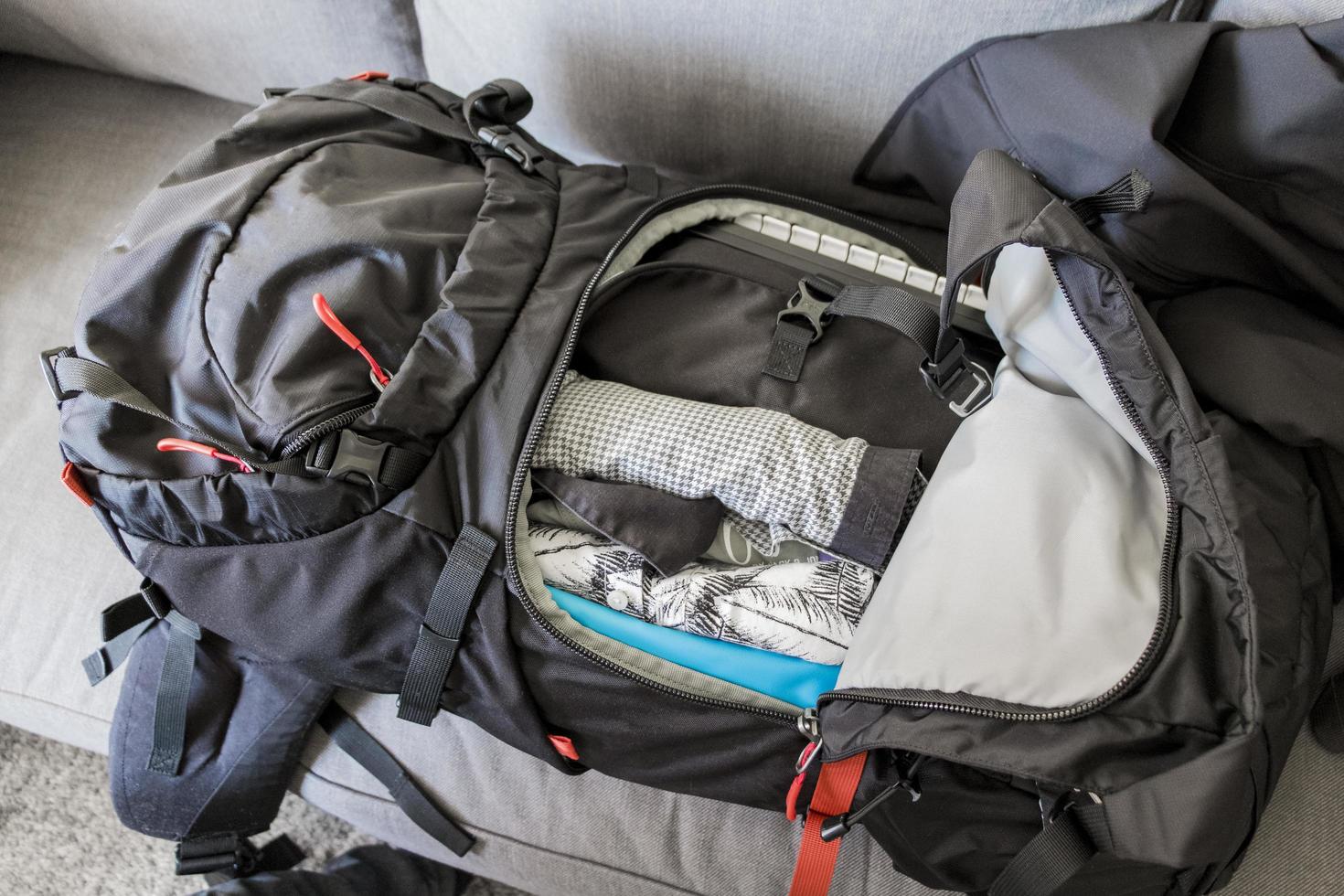 imballaggio zaino da viaggio nero rosso imballato, vestiti e utensili da viaggio. foto