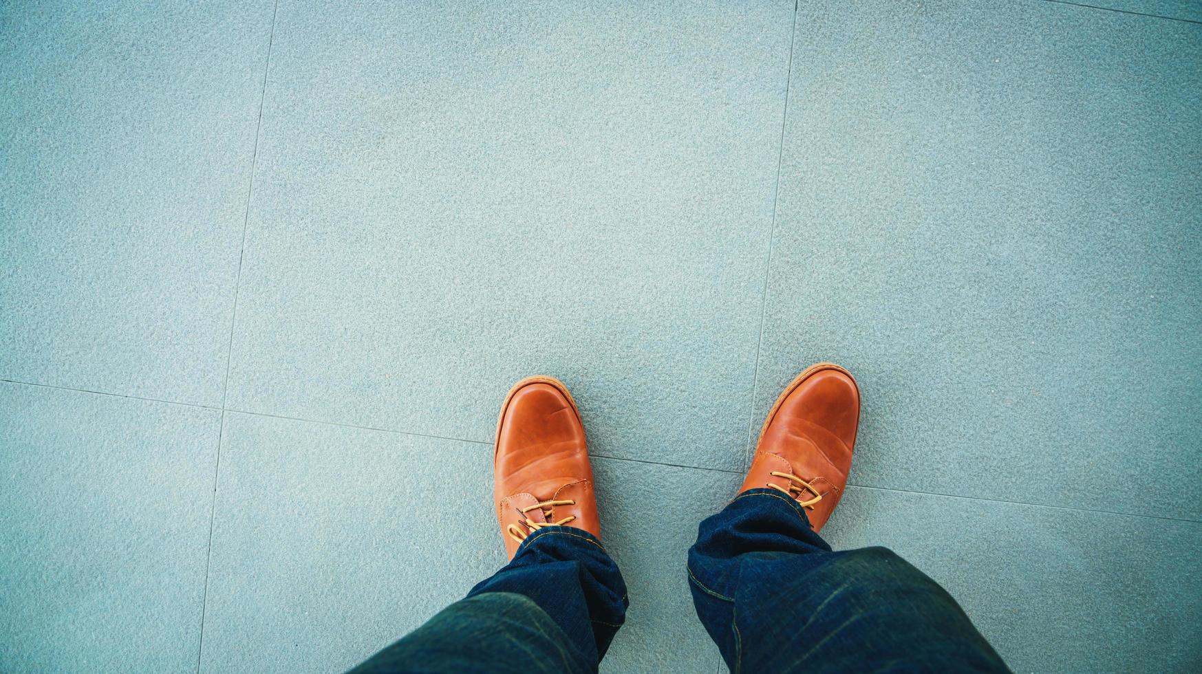 vista dall'alto di scarpe in pelle in piedi su sfondi di piastrelle per pavimenti in pietra foto