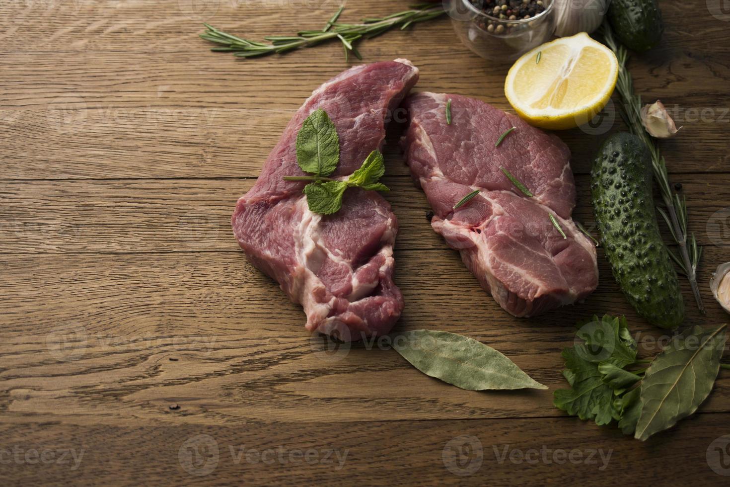 bistecche di carne succose crude pronte per essere arrostite su uno sfondo di legno foto