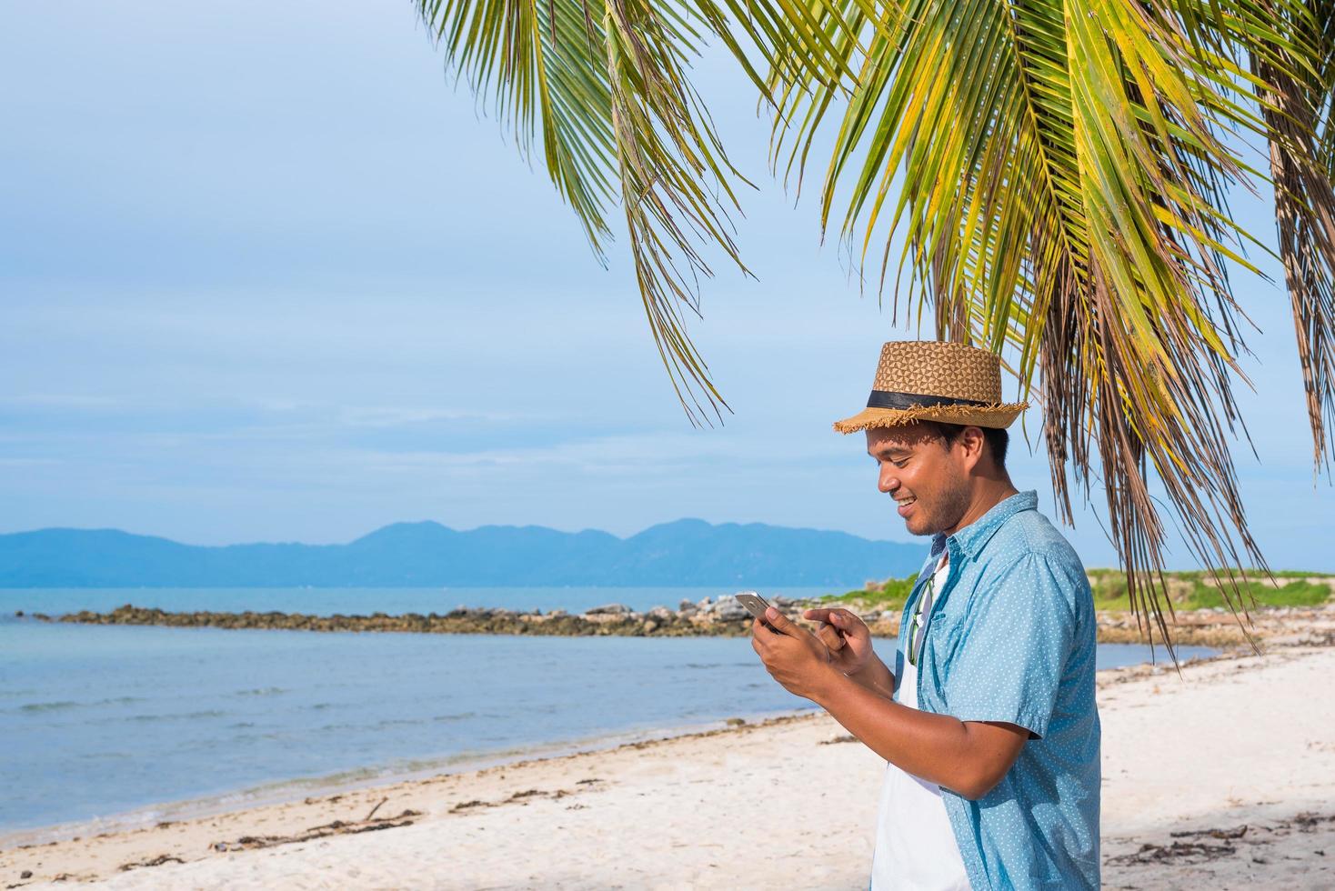 giovane uomo asiatico sulla spiaggia utilizzando smartphone. foto