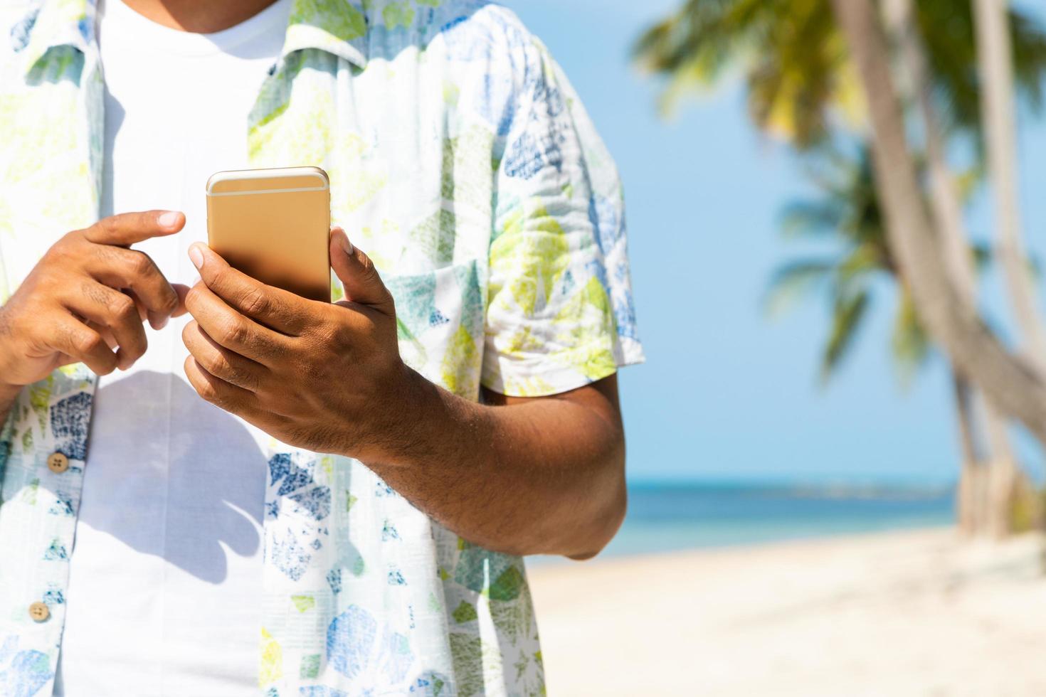 uomo sulla spiaggia utilizzando smartphone. foto