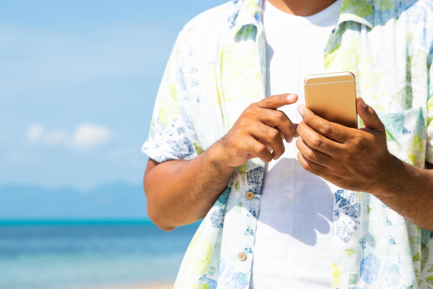 uomo sulla spiaggia utilizzando smartphone. foto