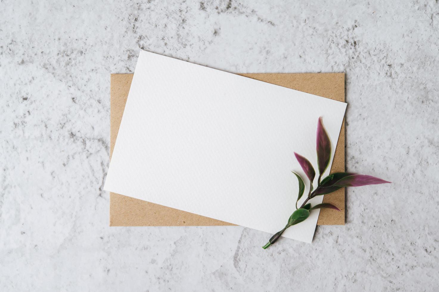 una carta bianca con busta e fiore è posta su sfondo bianco foto