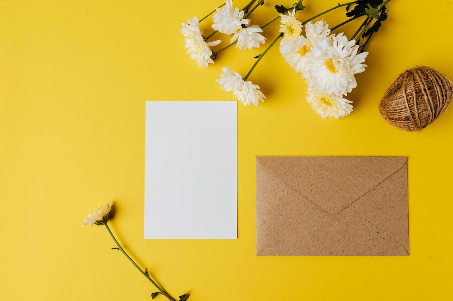 una carta bianca con busta e fiore è posta su sfondo giallo foto