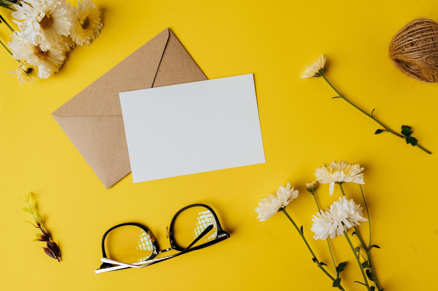 la carta bianca con busta, bicchieri e fiore è posta sul giallo foto