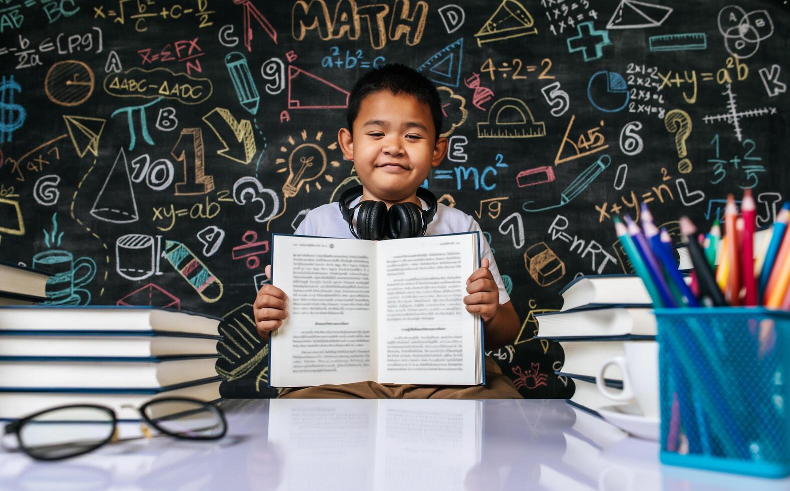 bambino seduto e mostra il libro in classe foto