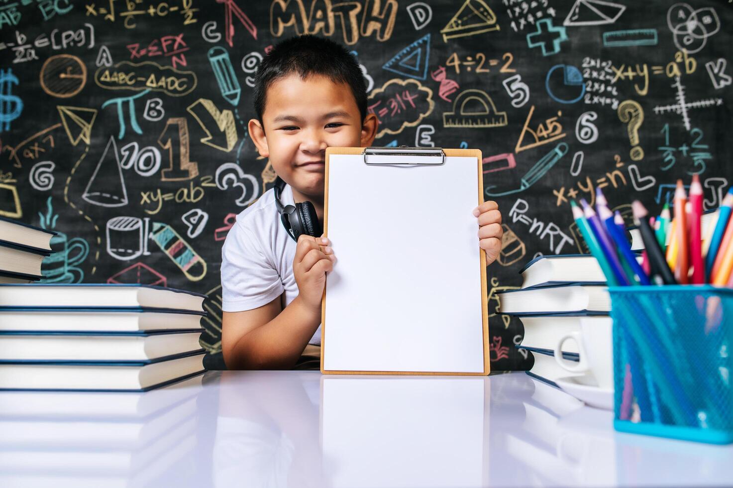 bambino seduto e mostra la lavagna degli appunti in classe foto