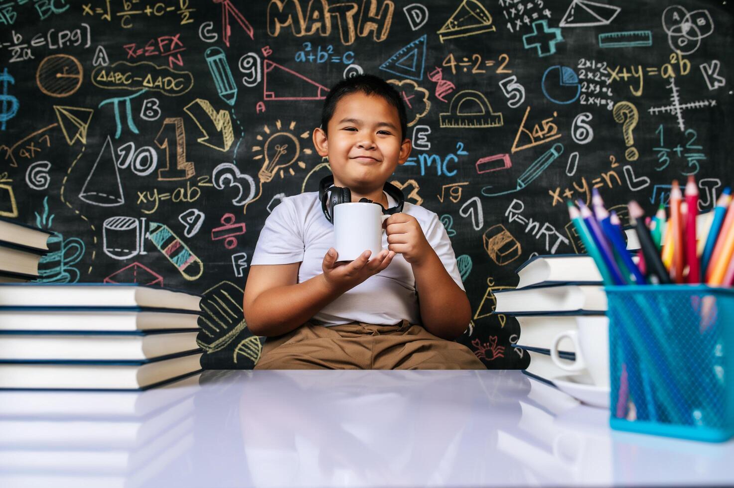 bambino seduto e tenendo la tazza in classe foto