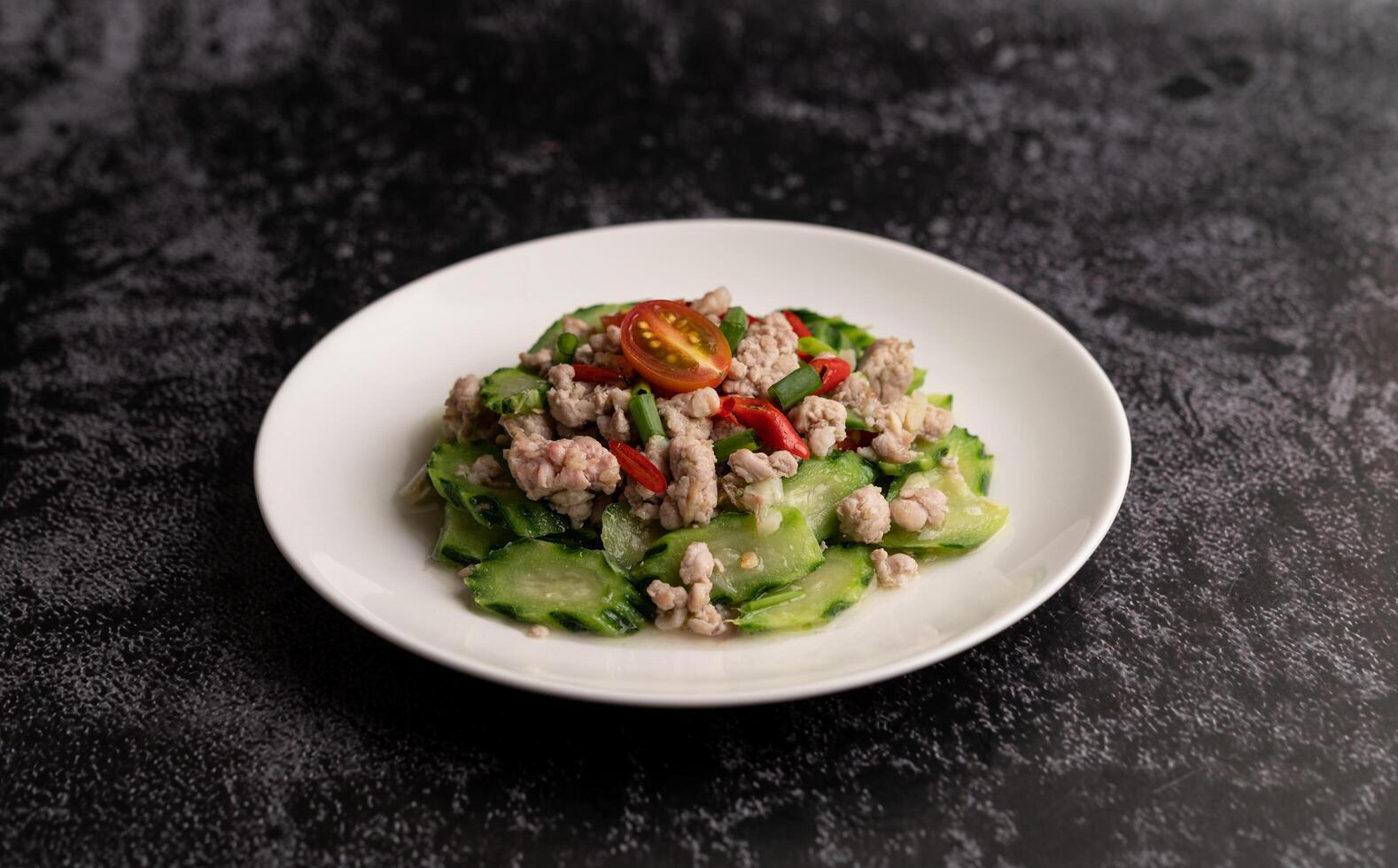 zucchine saltate in padella con carne di maiale macinata in un piatto bianco foto