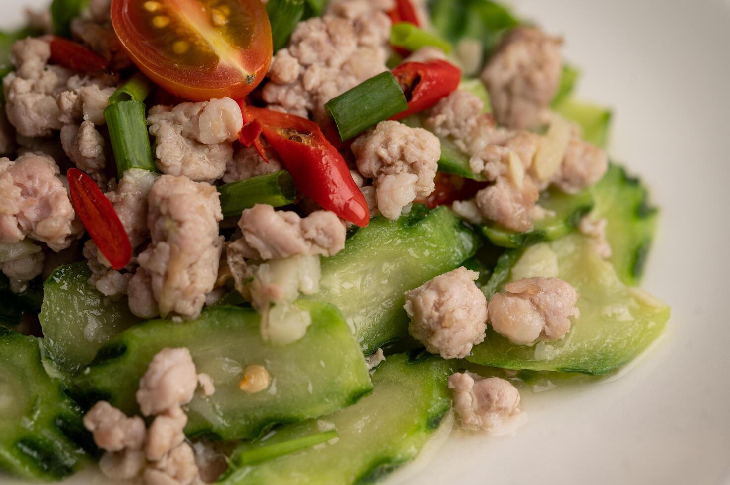 zucchine saltate in padella con carne di maiale macinata in un piatto bianco foto