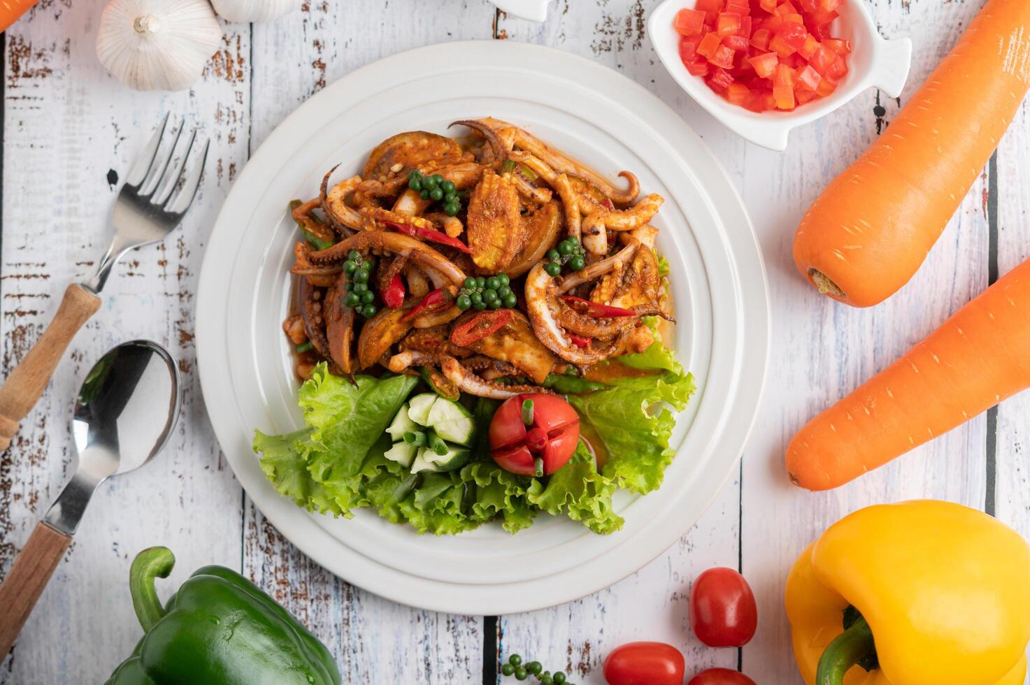 calamari saltati in padella con pasta di curry in piatto bianco. foto