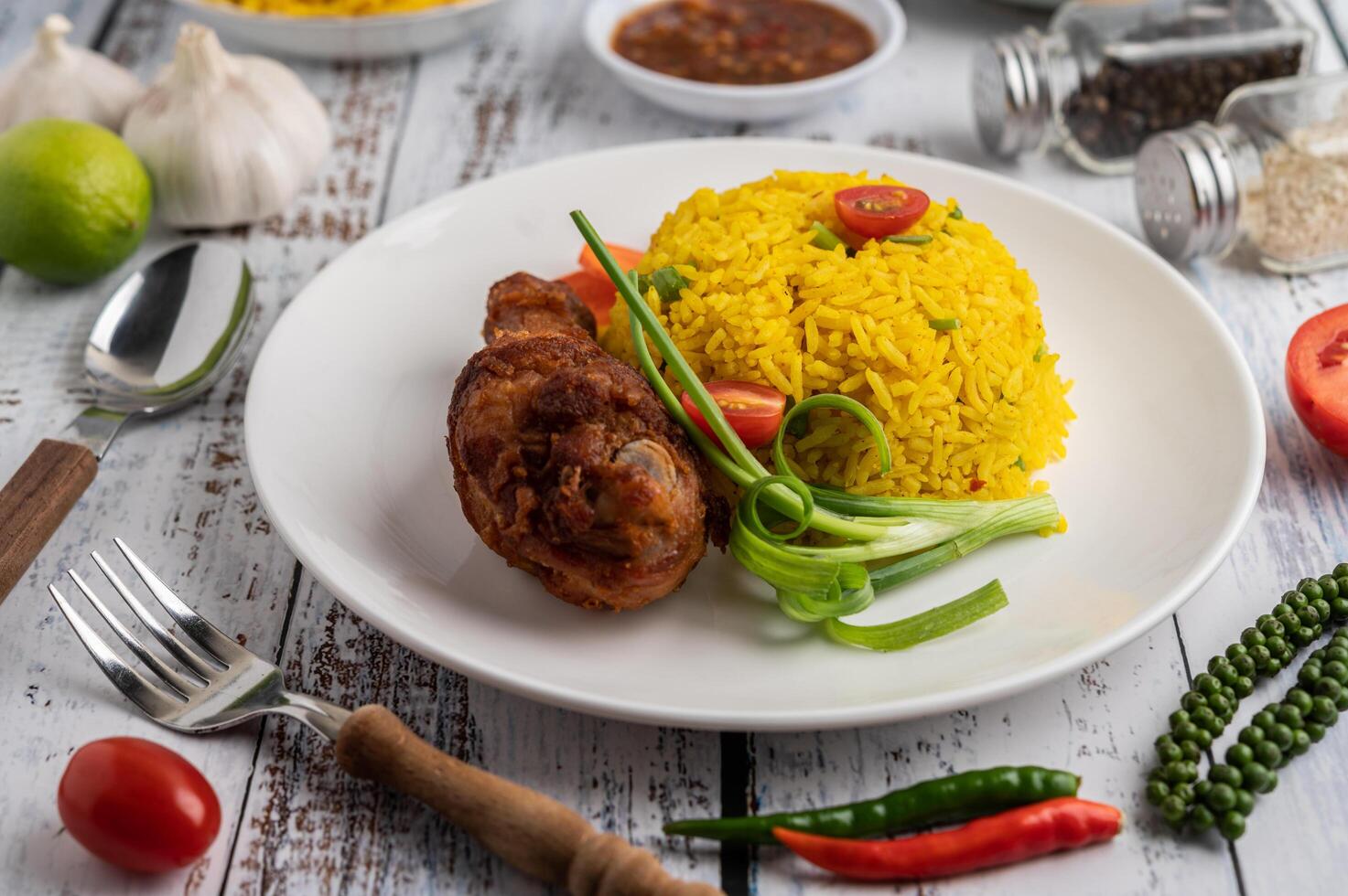 biryani di pollo in un piatto con spezie su un pavimento di legno bianco foto