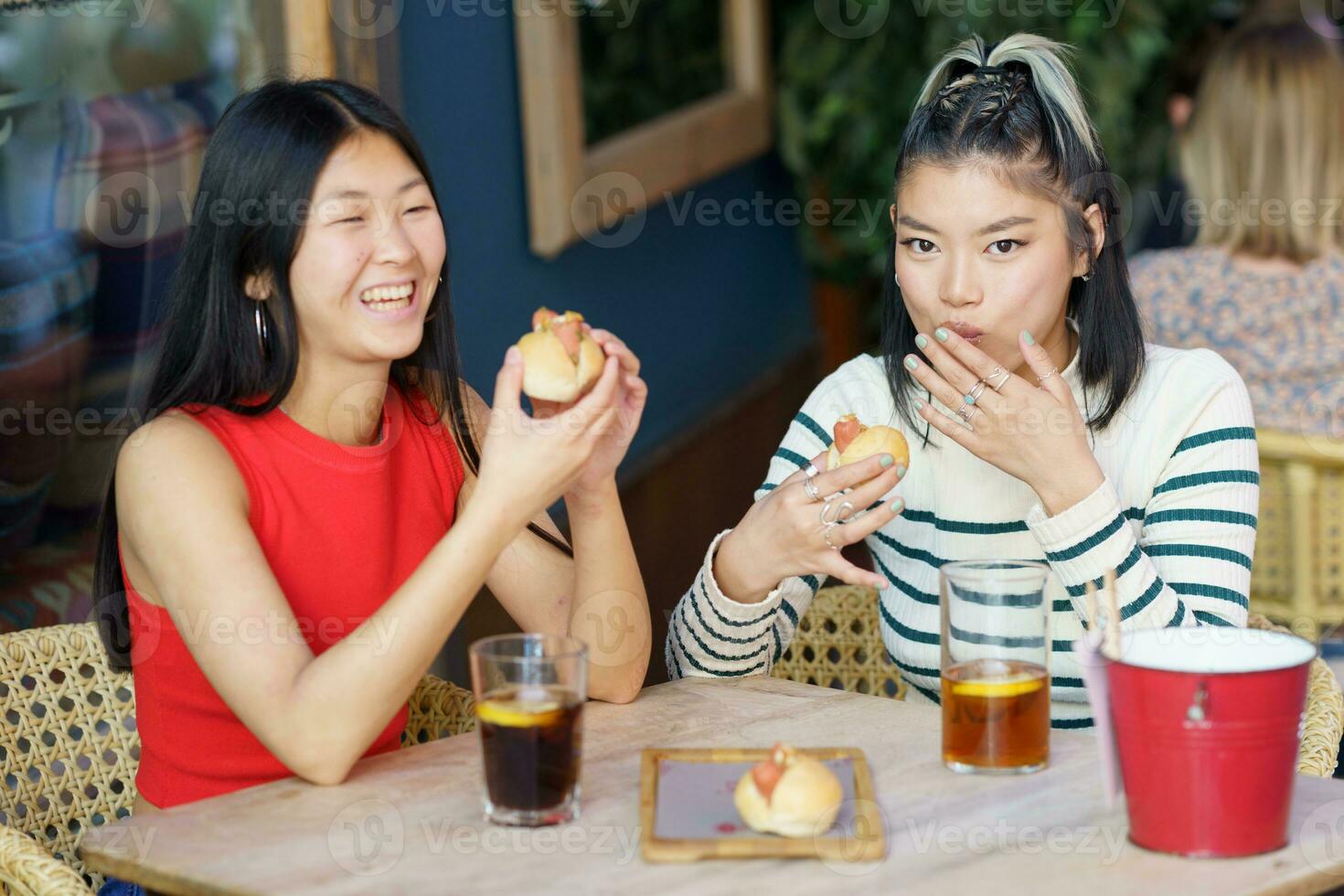 gioioso asiatico donne mangiare delizioso cibo durante pranzo insieme foto