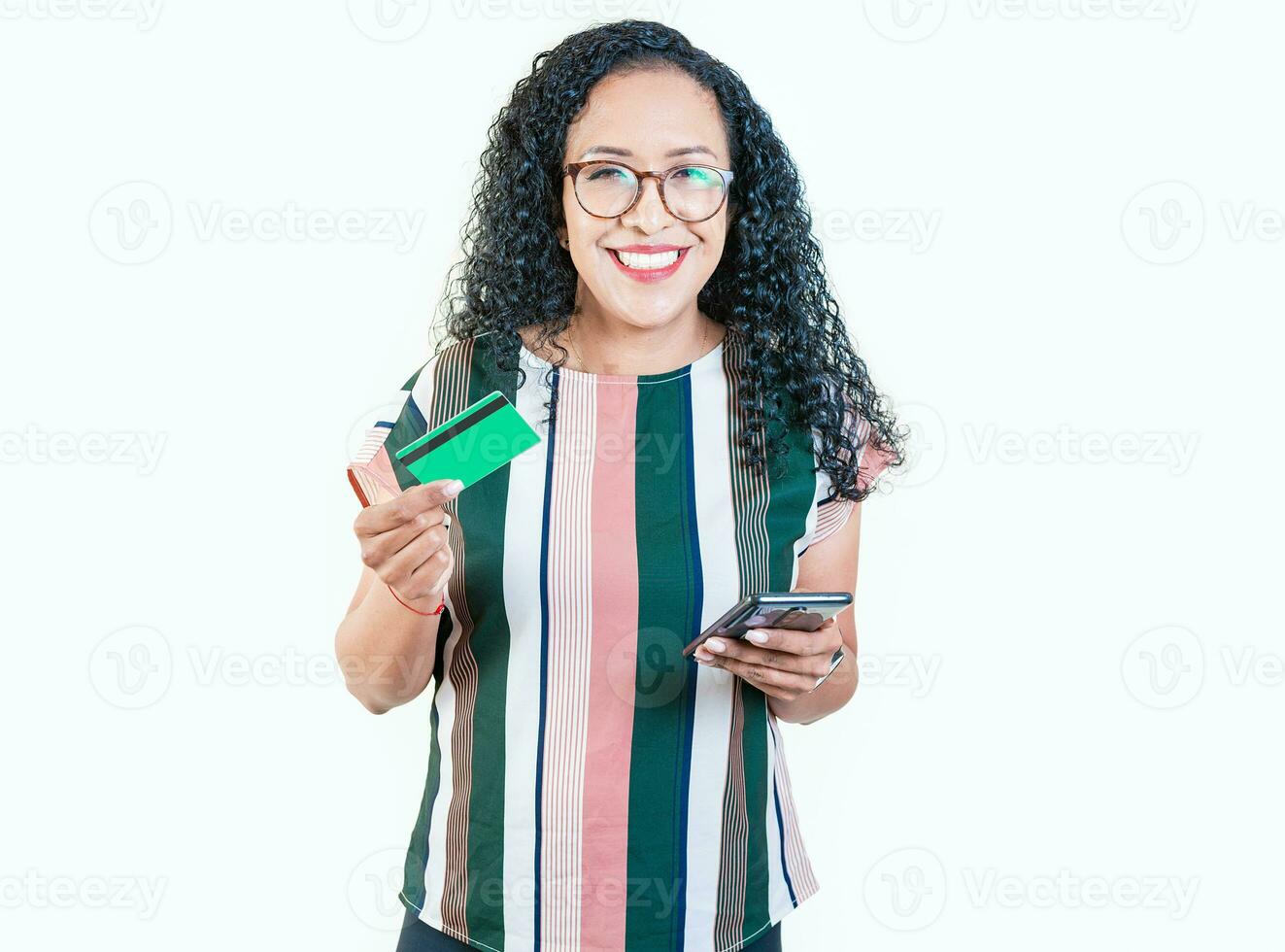 contento giovane donna fabbricazione in linea acquisti con cellula telefoni e credito carte. sorridente afro ragazza Tenere credito carta shopping in linea con Telefono isolato foto