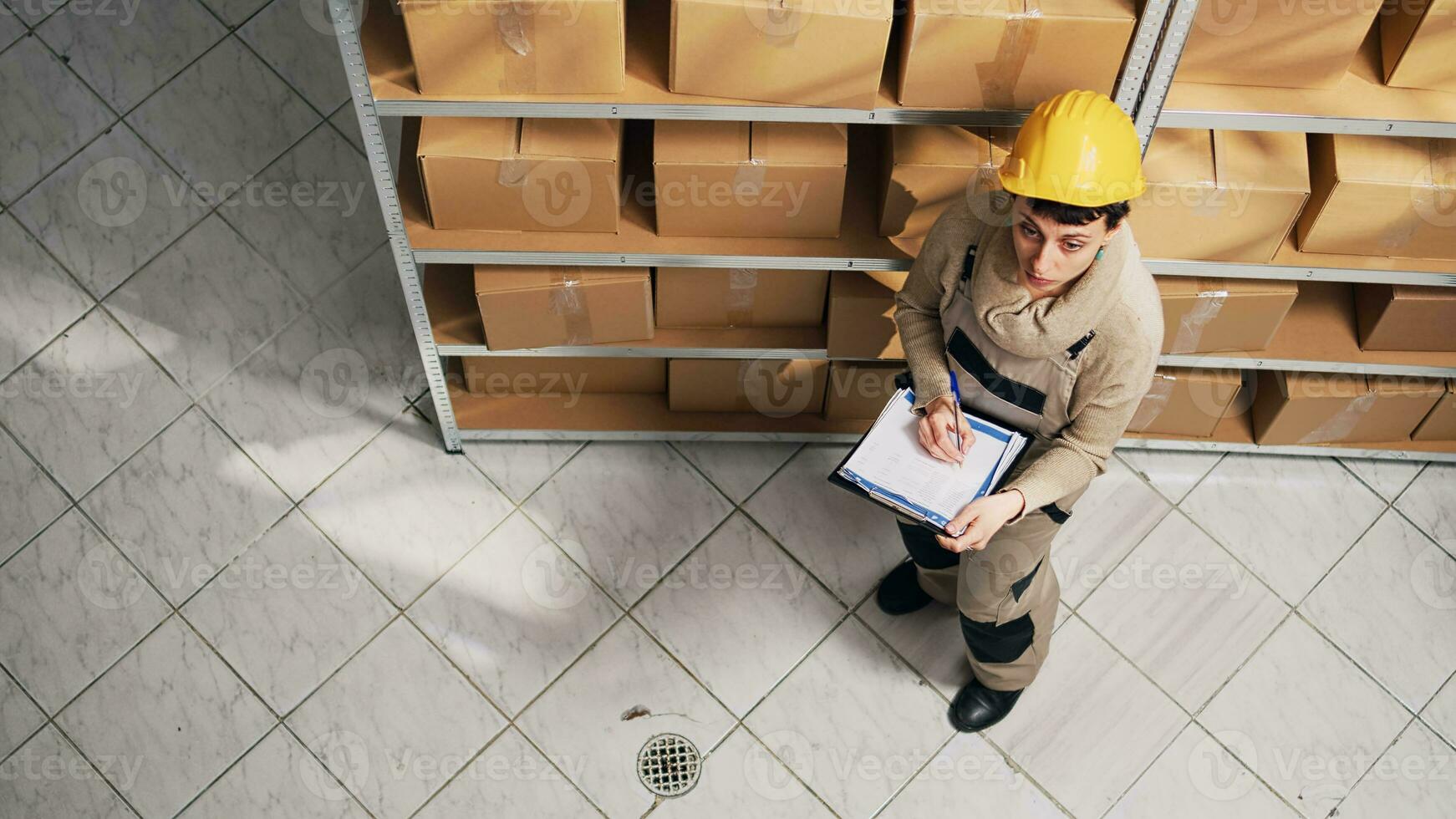 magazzino manager l'esame elenco di merce su scaffali, guardare a cartone pacchi per Piano spedizione. supervisore con tuta da lavoro Lavorando nel deposito spazio con merce e carico, azione la logistica. foto