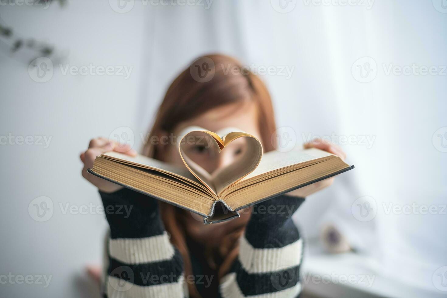 un' ragazza è Tenere un' libro. a forma di cuore pagine. lettura, sapendo, apprendimento foto